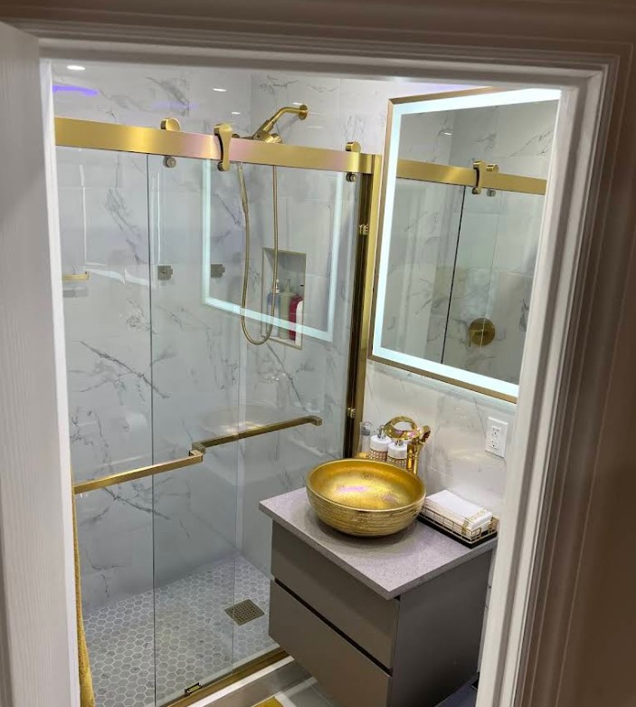 Bathroom featuring a gold sink and shower, showcasing a stylish renovation by Alliance General Construction in a modern apartment.